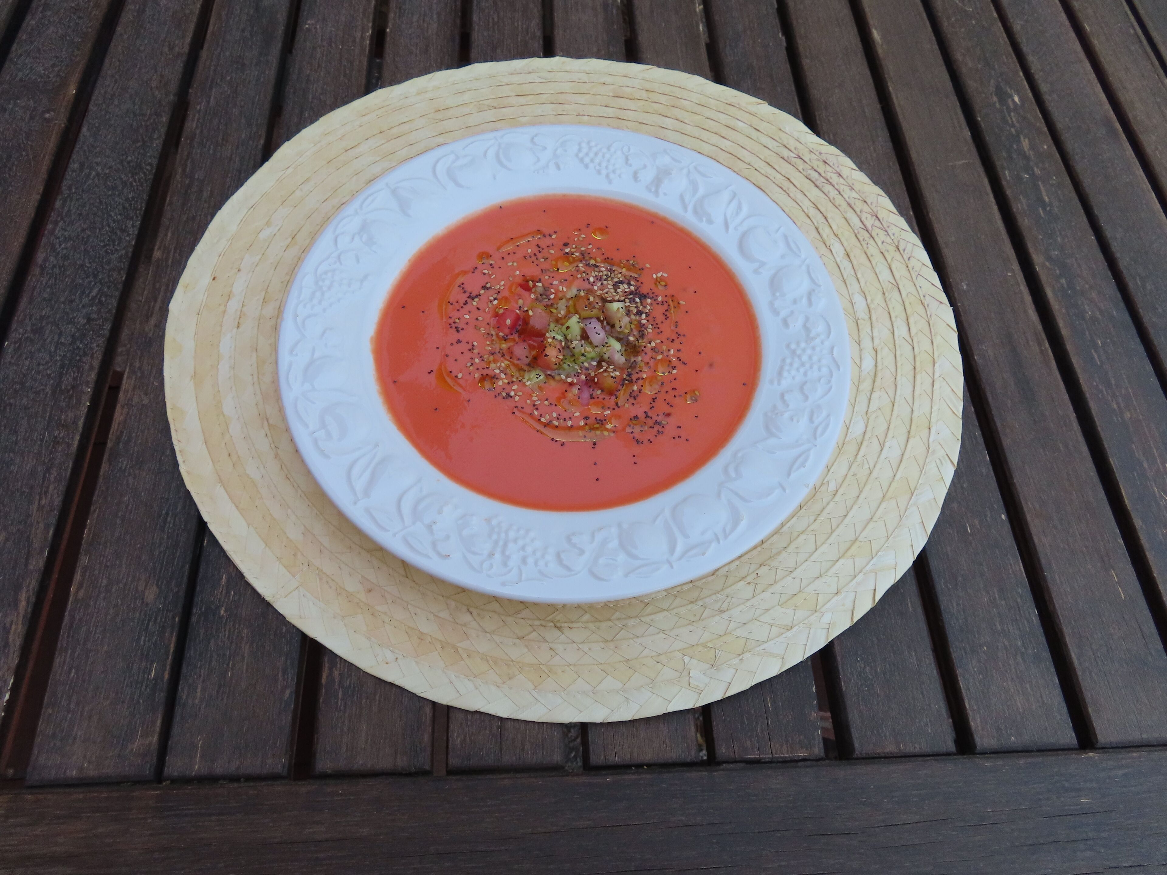 A bowl of tomato soup on a woven mat.