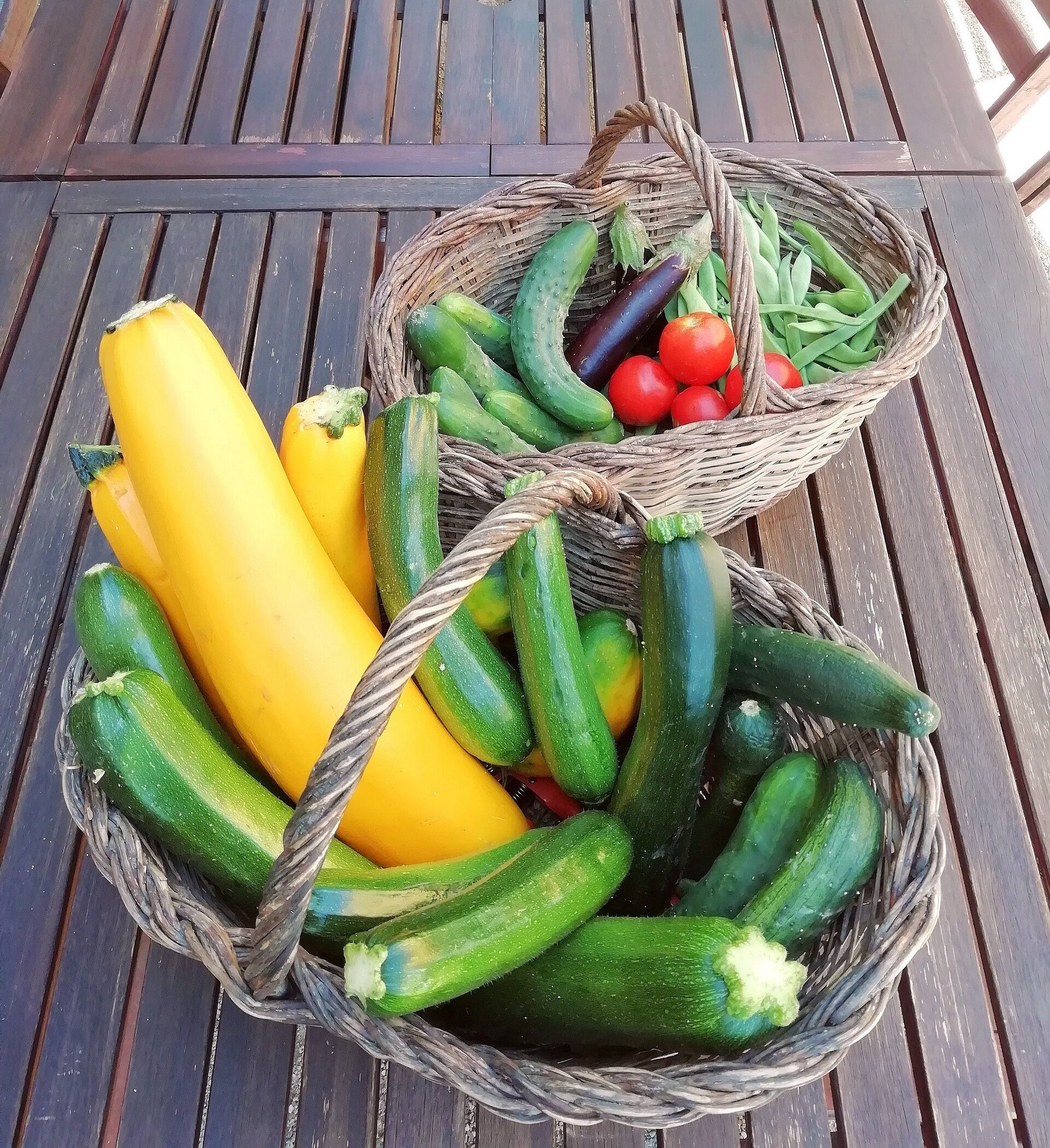 A wicker basket filled with vegetables on a wooden table.