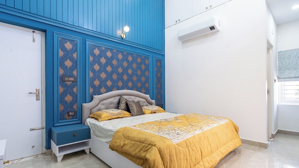 A bedroom with a bed, nightstand, and blue wall paneling.