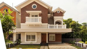 A two-story house with a balcony, a front door, and a small garden area.