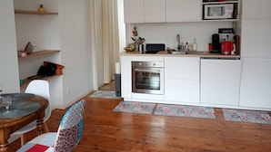 Eine kleine Küche mit weißen Schränken, einer Mikrowelle, einem Backofen und einer Kaffeemaschine.