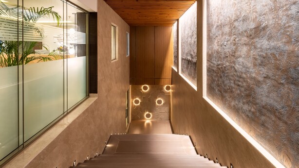 A modern staircase with a wooden finish, glass walls, and recessed lighting. - Foxtrail Sector 60- AM Hotel Kollection (Sohna)