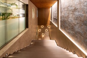 Un escalier moderne avec des finitions en bois, des murs en verre et un éclairage encastré.