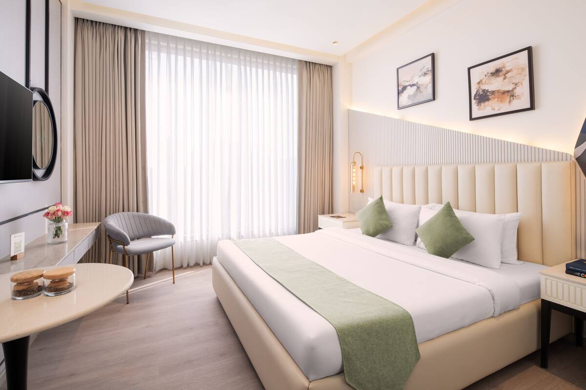 Une chambre d’hôtel moderne équipée d’un grand lit, d’un bureau, d’une chaise et d’un téléviseur.