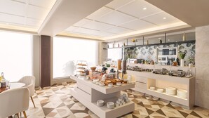 A modern breakfast area with a buffet setup, including various food items and a coffee station. - Foxtrail Sector 60- AM Hotel Kollection (Sohna)