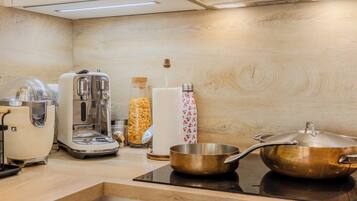 A kitchen with a toaster, coffee maker, and a pot on a stove.