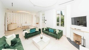Ein modernes Wohnzimmer mit grünen Sofas, einem weißen Couchtisch und einem Kamin.