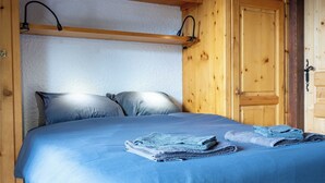 A bed with blue bedding and two folded towels, wooden walls, and a door with a metal handle. - 1BDR/4P apartment with balcony and parking- Megève (Megève)