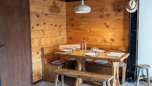 A wooden dining area with a table set for four, benches, a hanging light fixture, and a door. - 1BDR/4P apartment with balcony and parking- Megève (Megève)