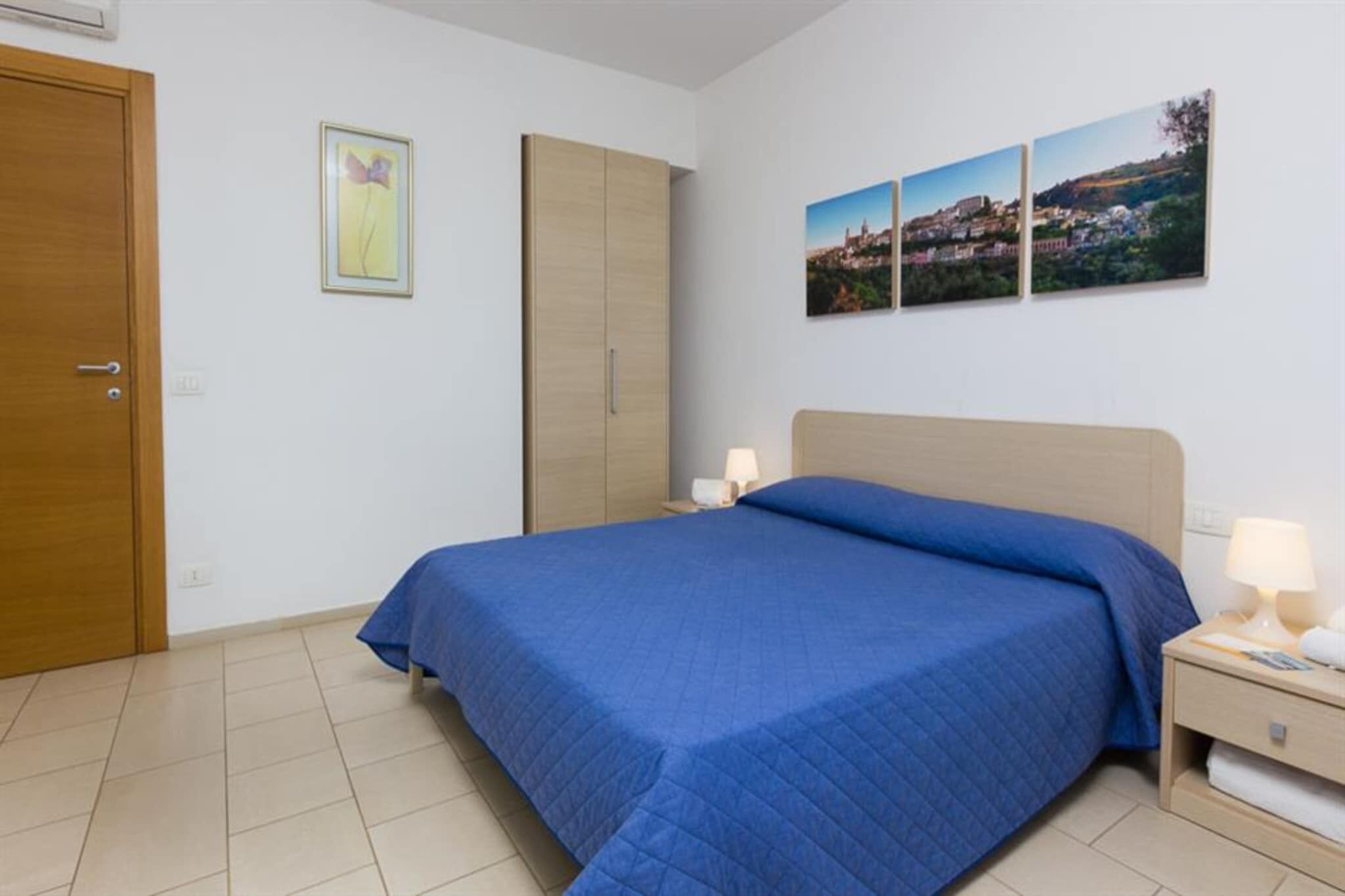Un dormitorio con cama, armario, mesita de noche y decoración en la pared.