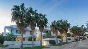 A modern hotel with a white facade, palm trees, and a staircase leading to the entrance. - Studio in Scoglitti, Sizilien (MARINA DI RAGUSA (RAGUSA))