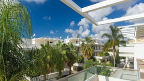 A modern hotel with multiple white buildings, a glass balcony, and lush greenery. - Studio in Scoglitti, Sizilien (MARINA DI RAGUSA (RAGUSA))