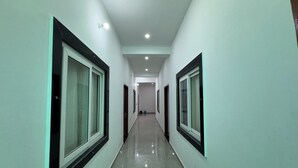 A long, narrow hallway with glass doors on both sides, leading to a room at the end. - Shri Guru Kripa Dham (Mathura)