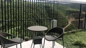 A balcony with a black metal fence, two round tables, and two wicker chairs. - G&R Talisay Property (Talisay)