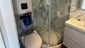 A modern bathroom with a glass-enclosed shower, a toilet, and a sink. - Super nice houseboat with fantastic views! (Molkwerum)
