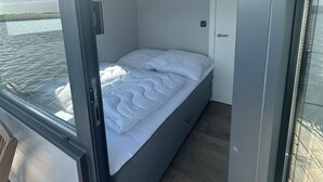 A bedroom with a bed, a door, and a view of the water. - Super nice houseboat with fantastic views! (Molkwerum)