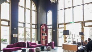 A spacious lobby with large windows, a red bookshelf, and modern seating arrangements. - 22 Macalisterz by Mana Mana (George Town)