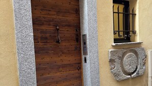 A stone-framed wooden door with a metal handle and a small window with metal bars.