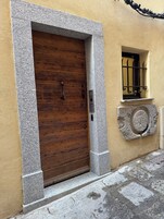 Una puerta de madera enmarcada en piedra, con manija de metal y un pequeño ventanal con barrotes.