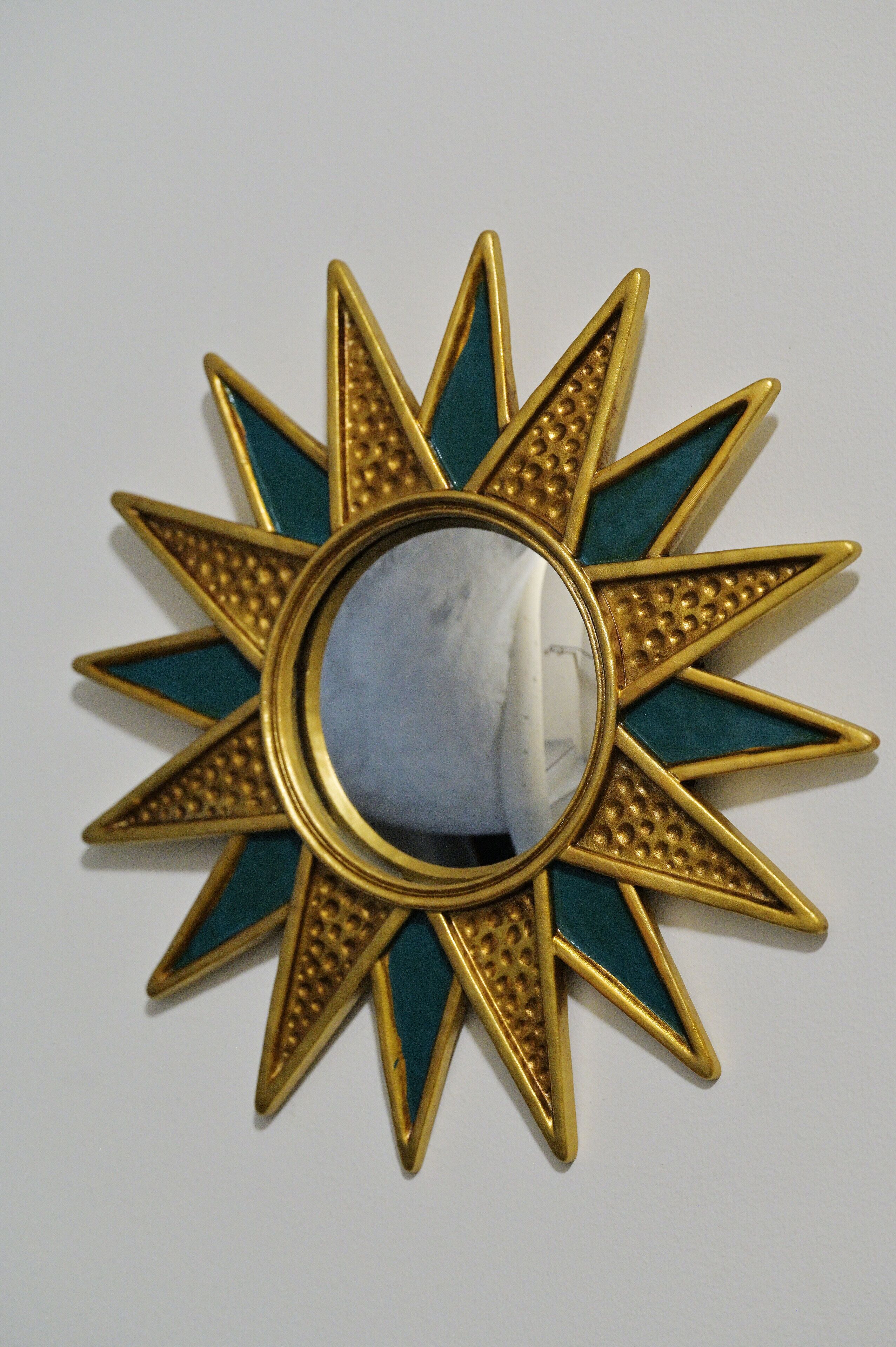 Um espelho decorativo em forma de sol, com uma superfície refletora no centro.