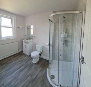 A bathroom with a toilet, sink, and shower. - Crittlewood Guest House (Gainsborough)