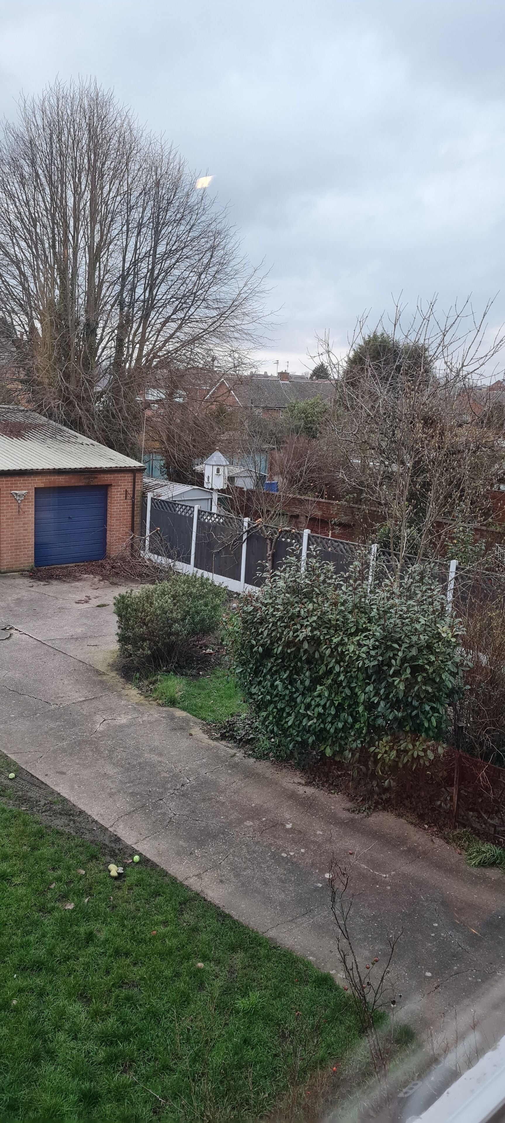 A residential area with a garage, a fenced yard, and a house in the background.