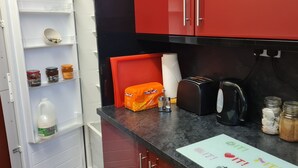 A kitchen with a refrigerator, a toaster, a kettle, and various jars on the counter. - Crittlewood Guest House (Gainsborough)