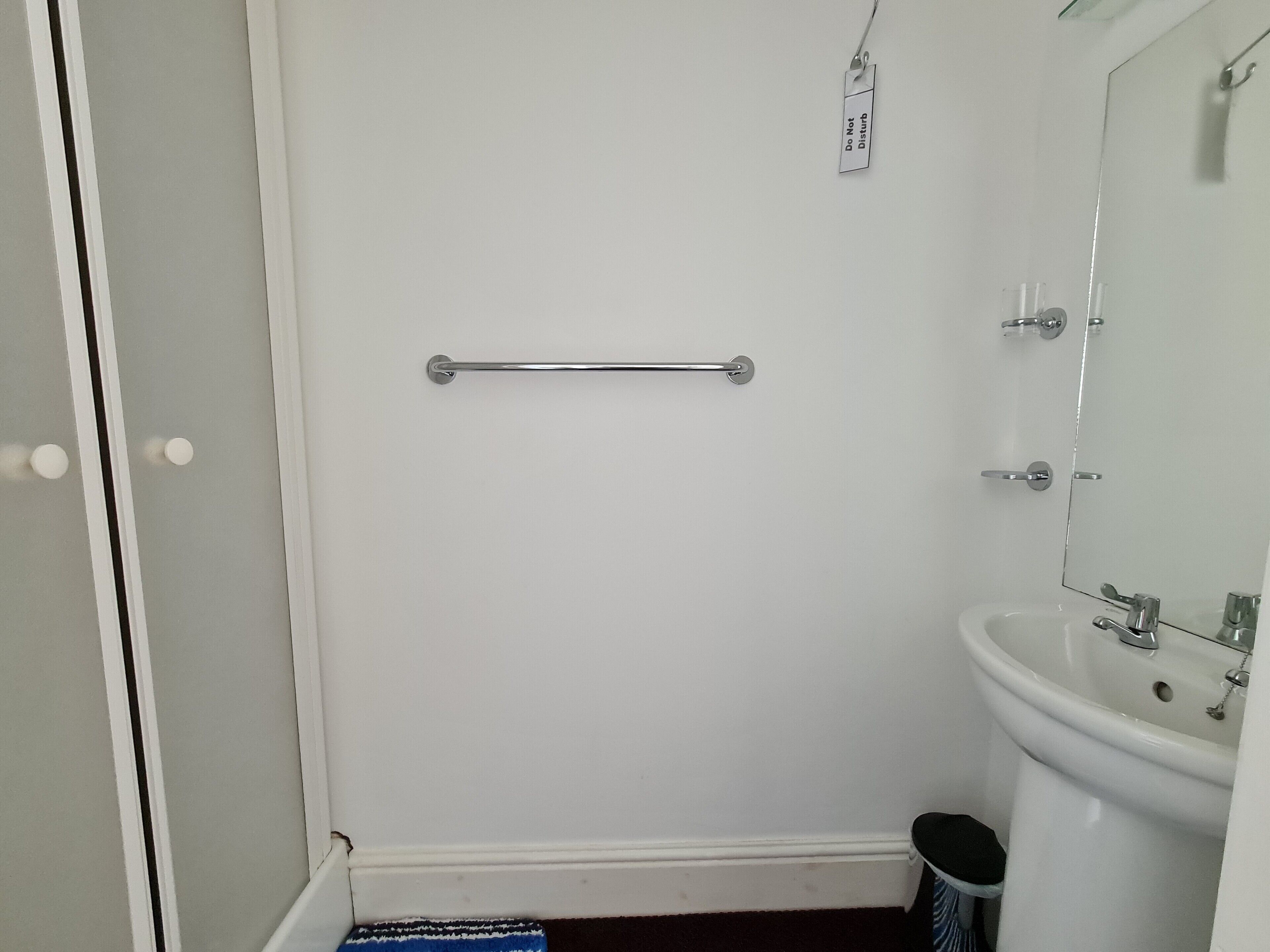 A bathroom with a white sink, mirror, and a towel rack.