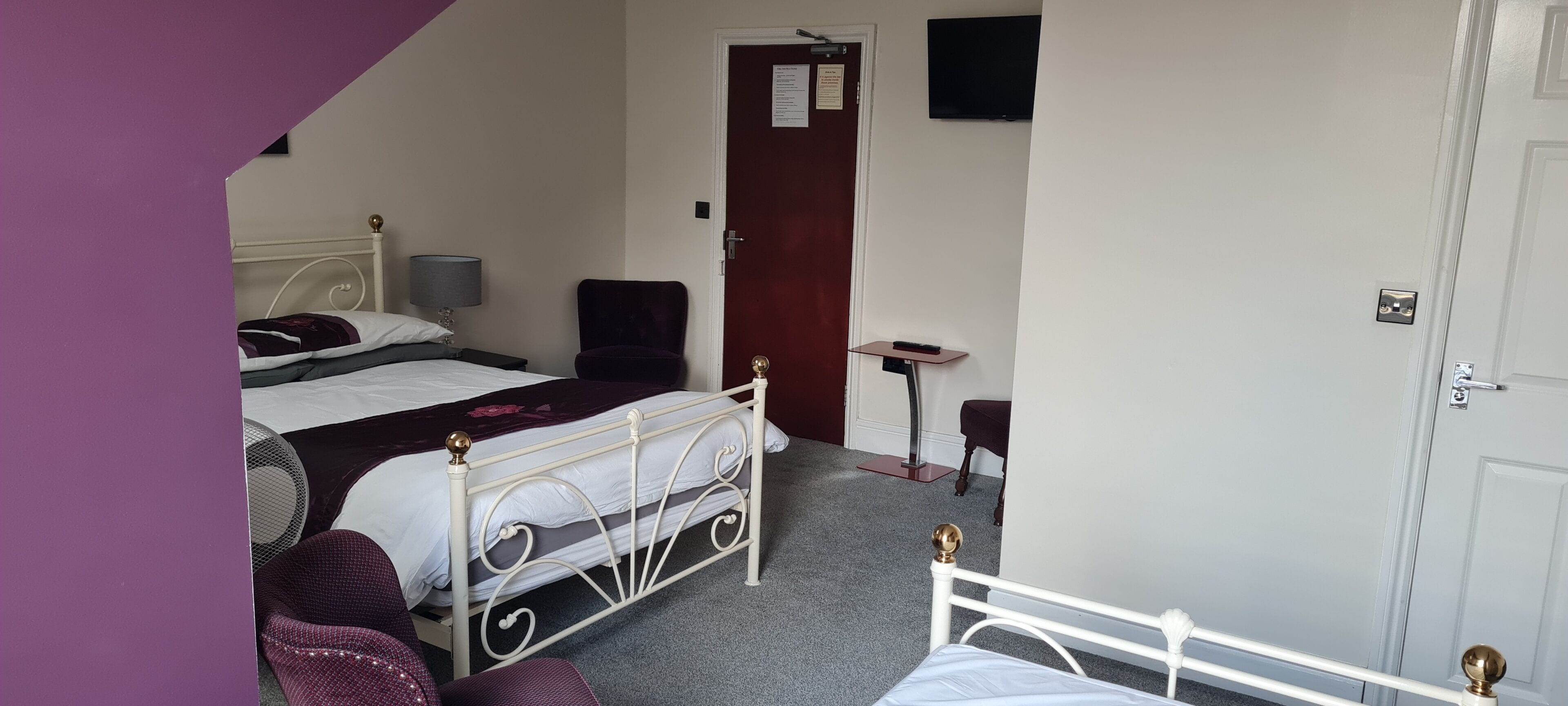 A bedroom with two beds, a desk, a chair, and a door.