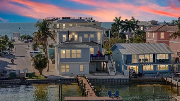A waterfront property with multiple buildings, a dock, and a view of the ocean.