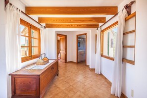 A hallway with wooden beams, a wooden dresser, and a view of a bathroom. - Can Tia, elegant villa with swimming pool and mountain views (Pollença)
