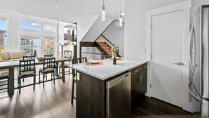 Una cocina moderna con una isla central, electrodomésticos de acero inoxidable y un comedor con muebles de madera.