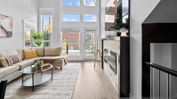 Un salón moderno con un sofá, una mesa de centro y vistas amplias a través de grandes ventanales.