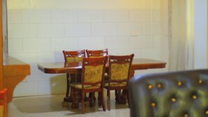 Un'area pranzo con tavolo e sedie, un divano e uno schienale piastrellato.