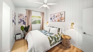 A bedroom with a bed, ceiling fan, wall-mounted light, window with curtains, and a plant. - Stylish Garden Retreat in Coconut Grove - Green (Coral Gables)