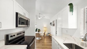 A modern kitchen with white cabinetry, a built-in oven, a microwave, and a stainless steel sink. - Stylish Garden Retreat in Coconut Grove - Green (Coral Gables)