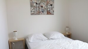 Un dormitorio con una cama, dos mesitas de noche y un cuadro colgado en la pared.