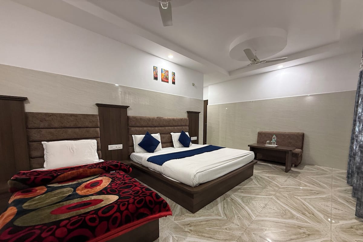 A hotel room with a large bed, a smaller bed, a desk, and a chair.