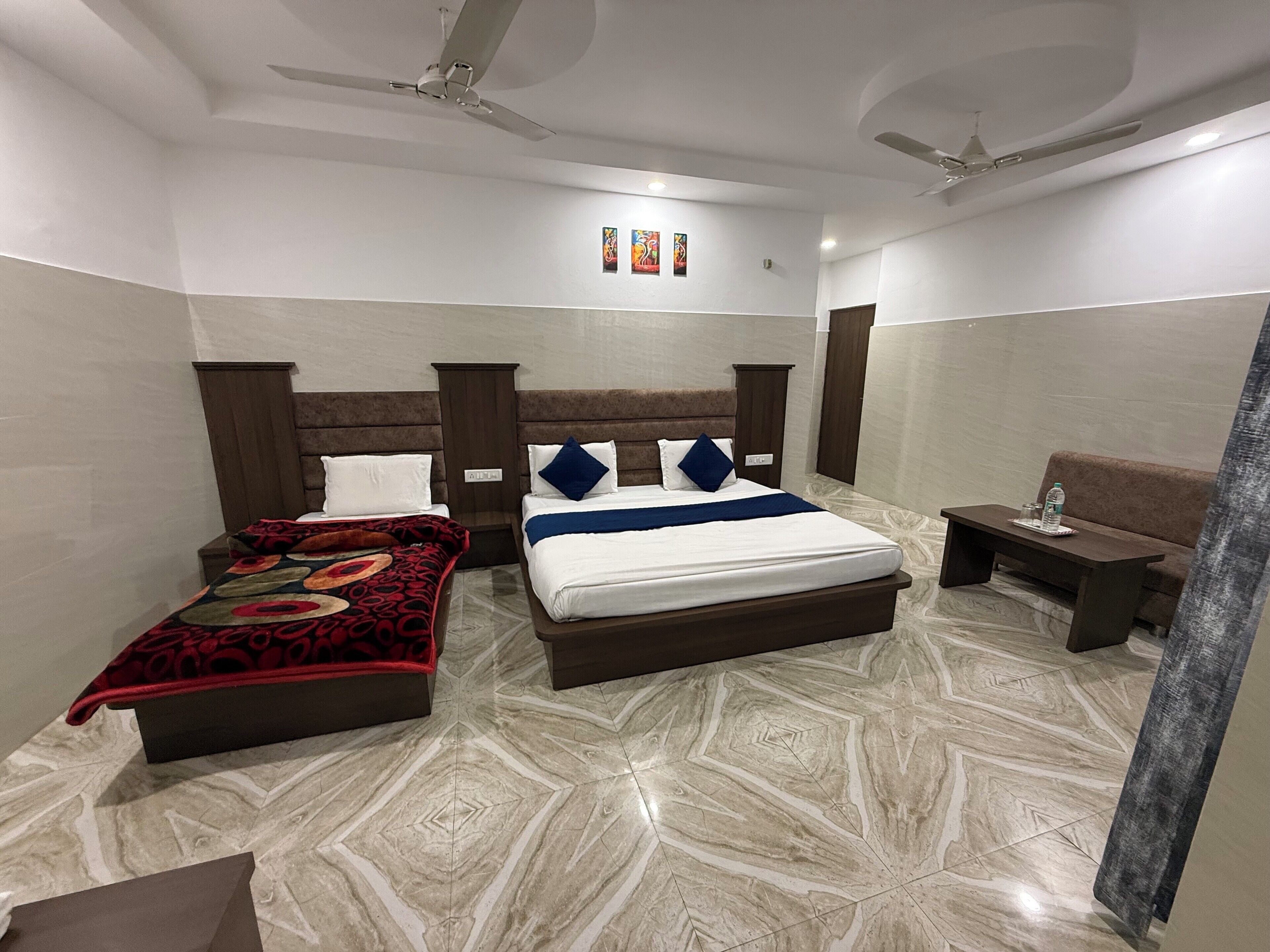 A hotel room with a large bed, a smaller bed, a desk, and a sofa.