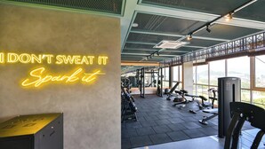 Een sportschool met een motiverende neonbord, fitnessapparatuur en grote ramen met uitzicht.