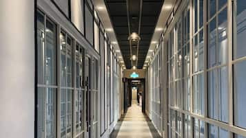 A corridor with glass doors, overhead lighting, and a visible sign.