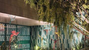 Una habitación con pared de diseño verde, una planta colgante y una verja metálica decorativa.