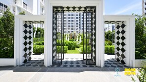 Een moderne gevel met een zwart-wit geometrisch patroon, een verzorgde tuin en een heldere lucht.