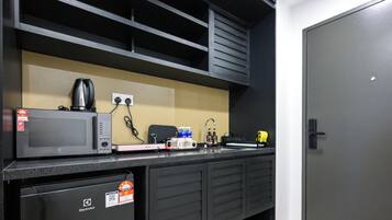 Una kitchenette equipada con microondas, cafetera y un refrigerador pequeño.