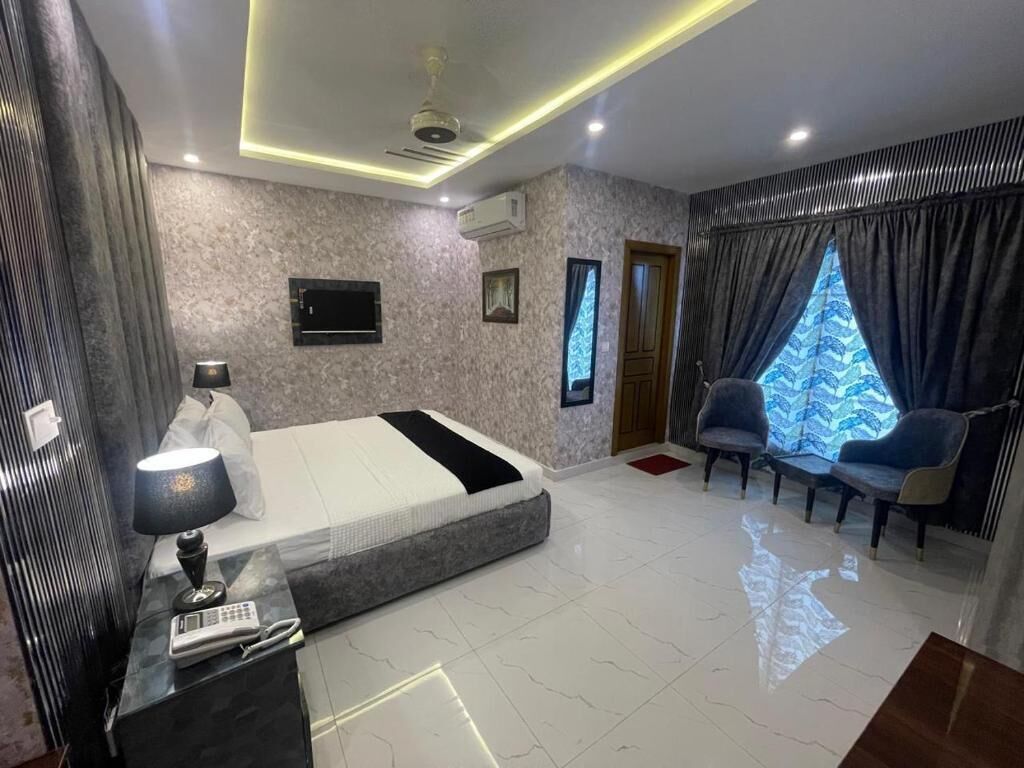 A modern bedroom with a bed, bedside table, lamp, and a TV.