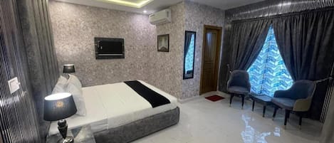 A modern bedroom with a bed, bedside table, lamp, and a TV.