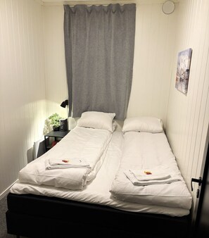 A small, single-room accommodation with two beds, a bedside table, a lamp, and a wall-mounted artwork. - Fresh, central apartment - Dorado (Tromsø)