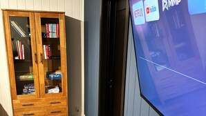 Un mueble de madera con cajones y estantes, una puerta con manija y una pared con una pantalla que muestra logotipos.