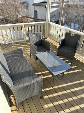 An outdoor deck with wicker furniture, including a sofa and two chairs, and a glass-top table. - Modern apartment with terrace - SOLIS (Tromsø)