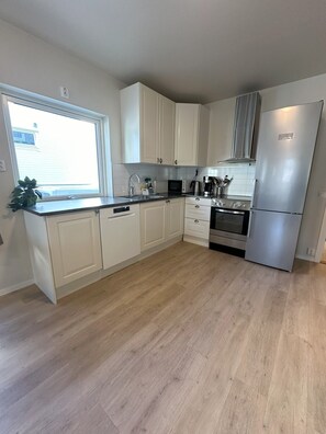 A modern kitchen with white cabinets, a stainless steel refrigerator, and a built-in oven. - Modern apartment with terrace - SOLIS (Tromsø)